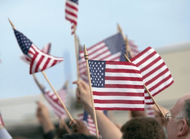 A group of people holding american flags in the air.