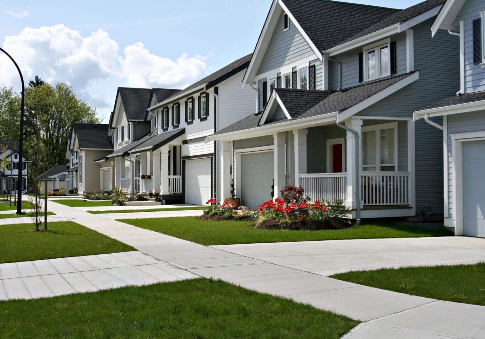 A row of houses with a sidewalk in front.